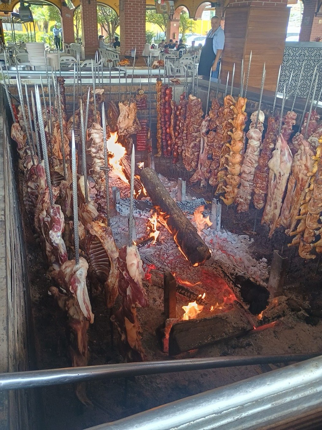 Borrego asándose en estacas junto a la leña
